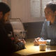 Morbius and his friend sit at a table.